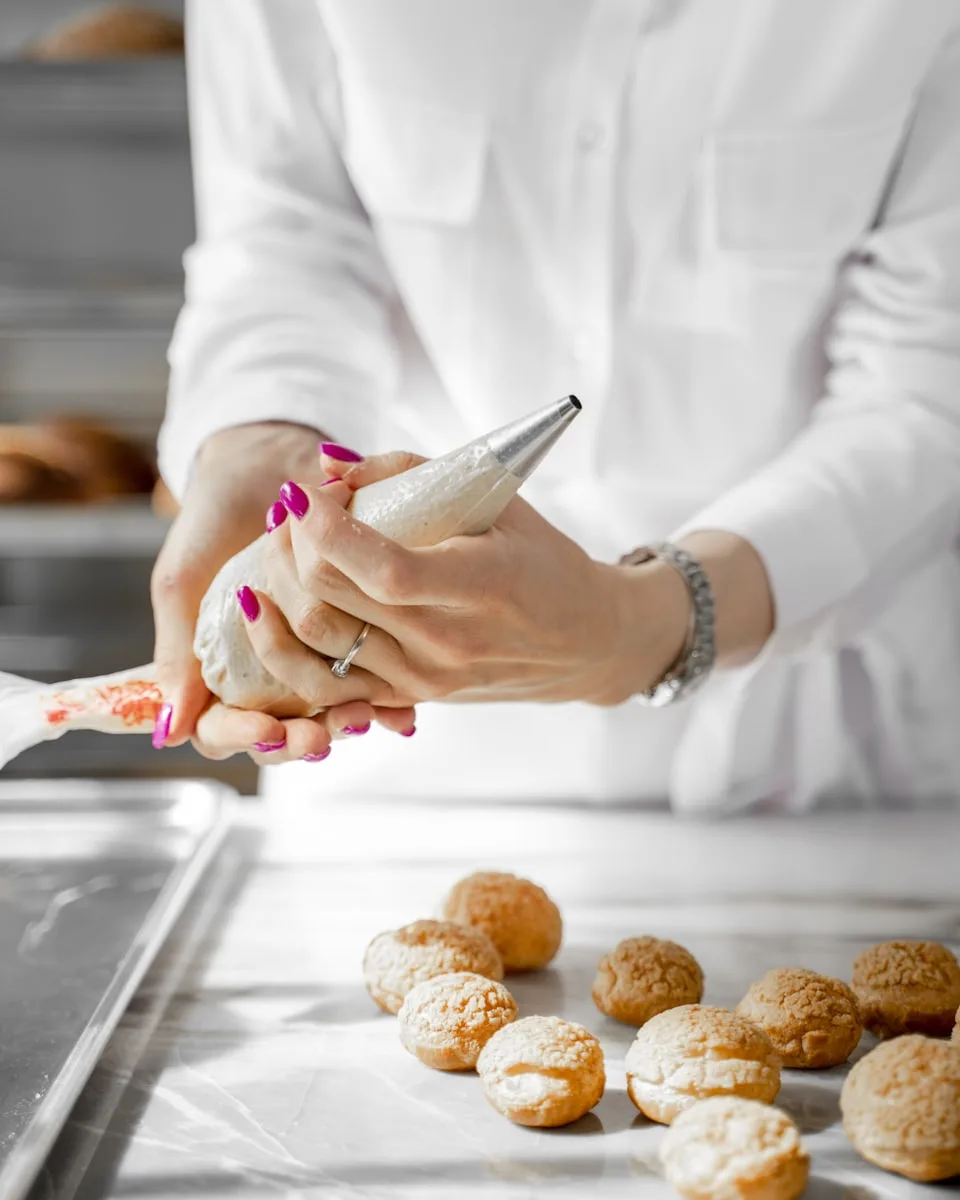 La pâtissière poche la crème sur les coques