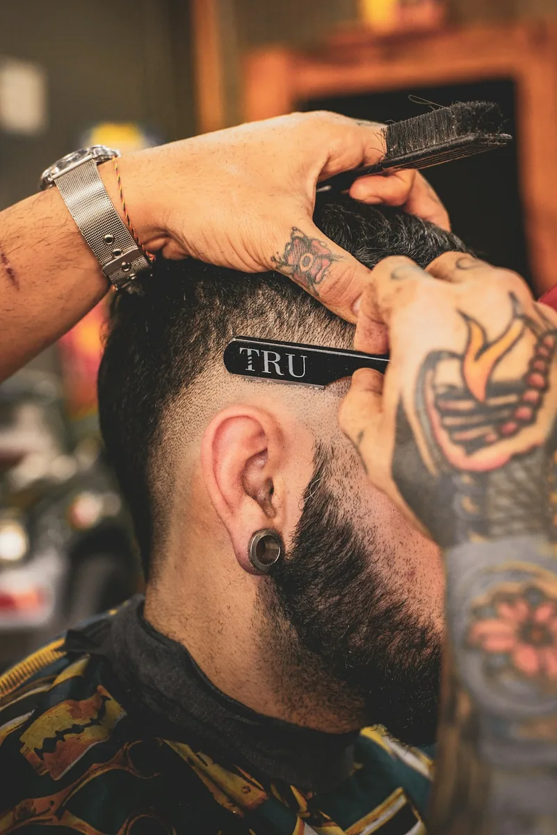Les mains tatouées de Karim reprennent un contour au rasoir