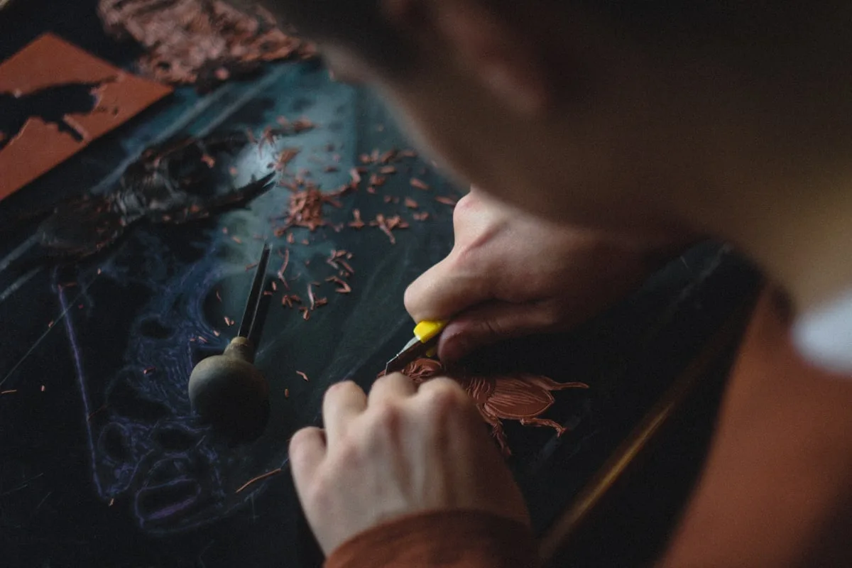 Des mains sculptent une planche de bois