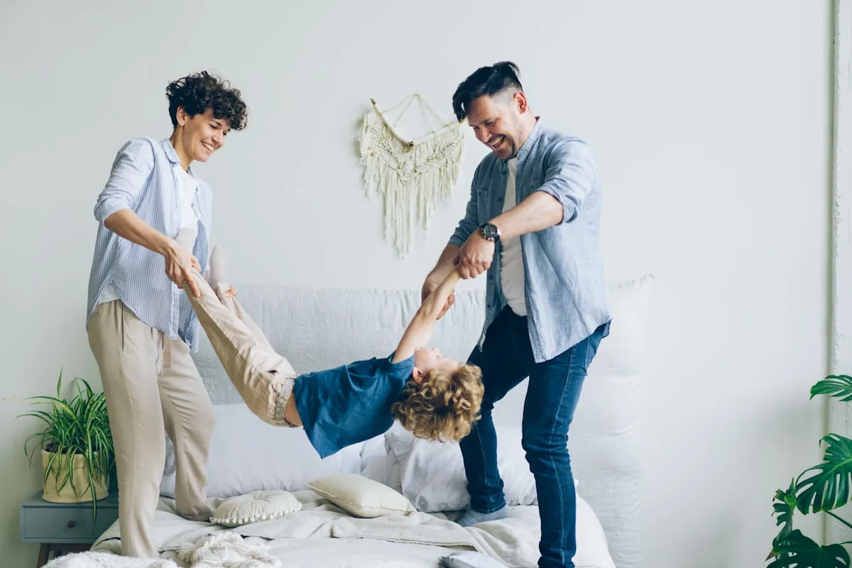 Les parents jouent avec l'enfant sur le lit