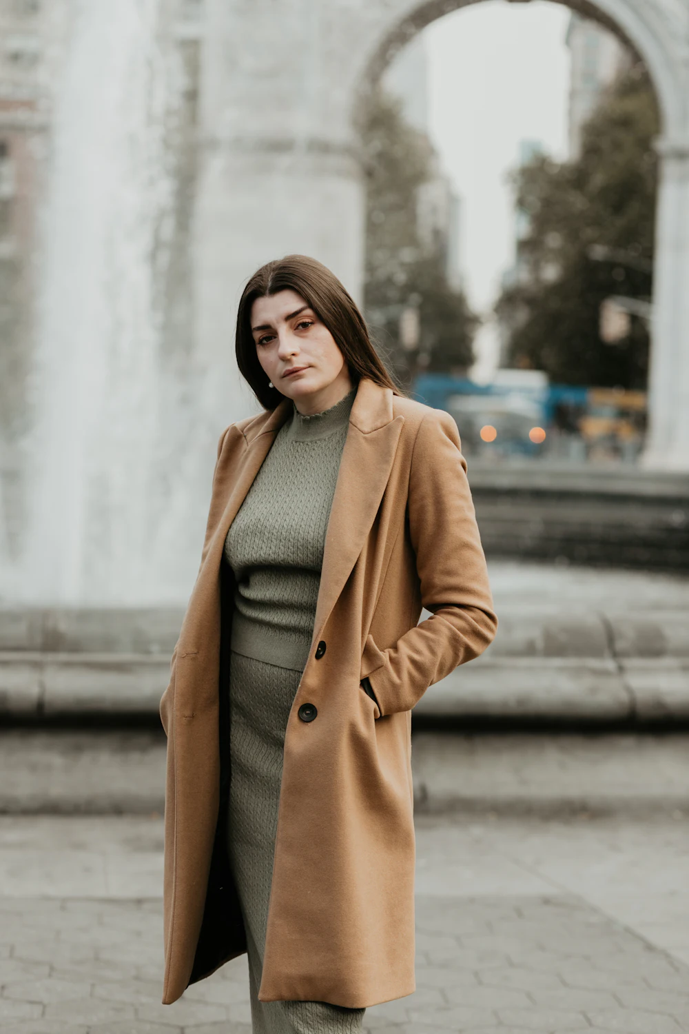 Une femme en manteau brun sur un trottoir, en pied