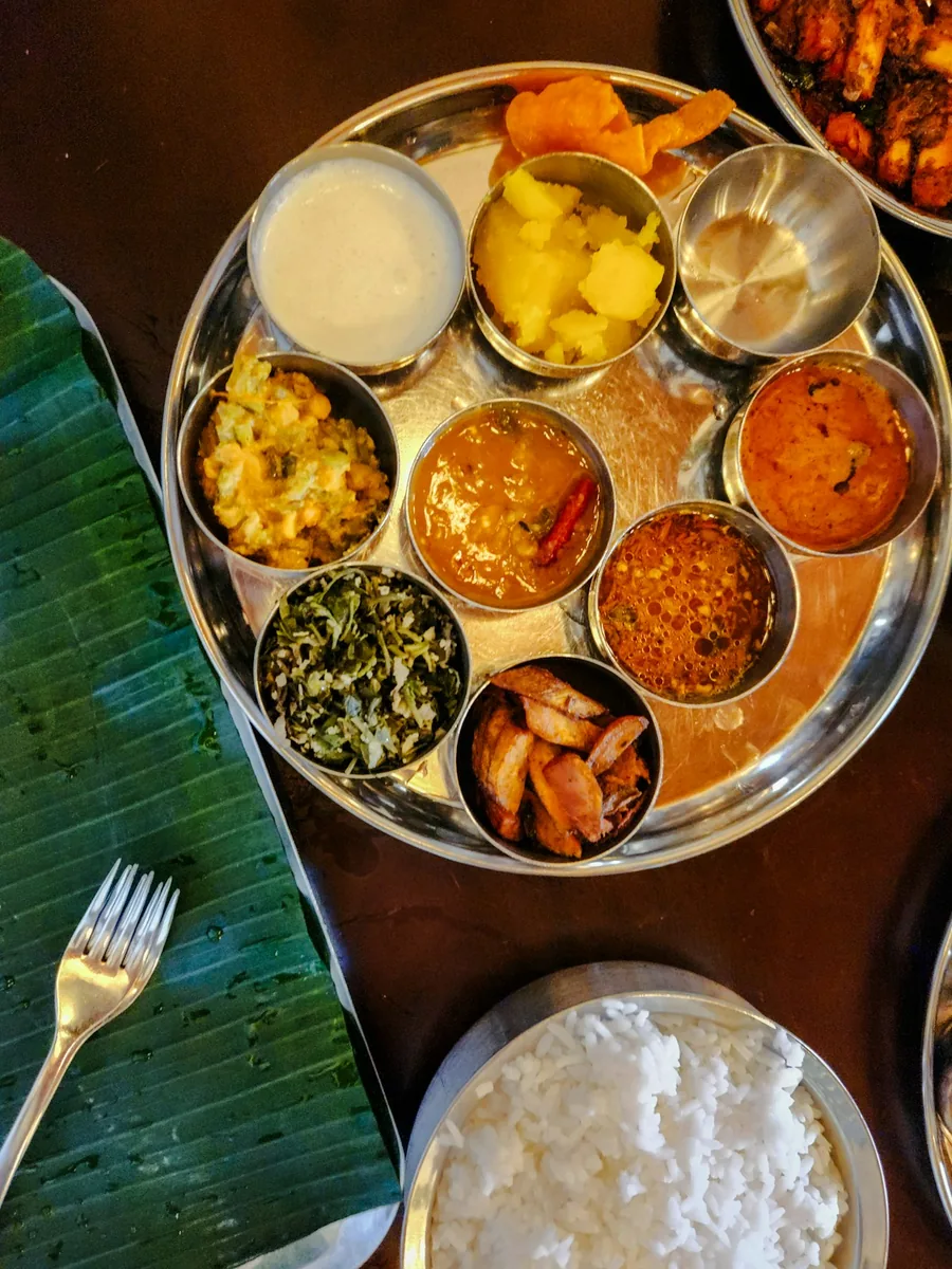 Un thali en coupelles d'inox posé près d'une feuille de bananier