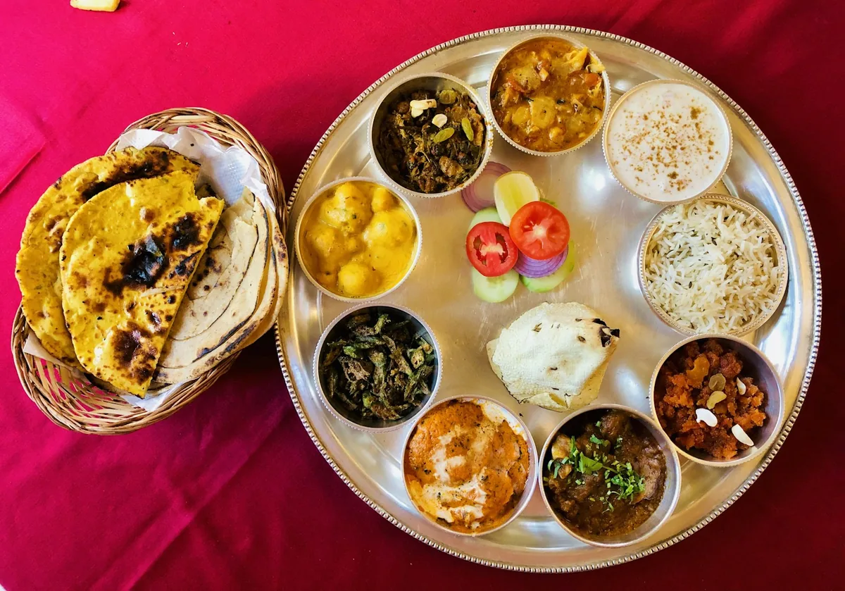 Un grand thali sur une nappe rose, des rotis en corbeille
