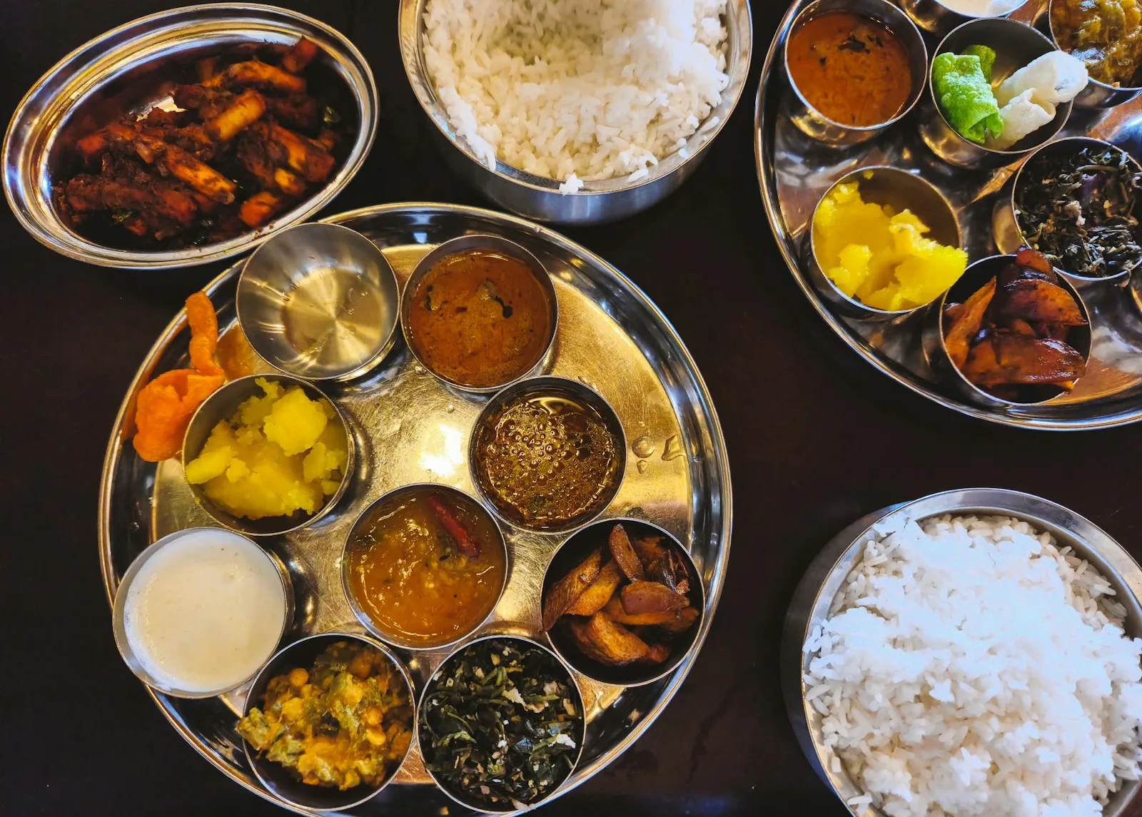 Des thalis vus du dessus, riz blanc et currys en coupelles