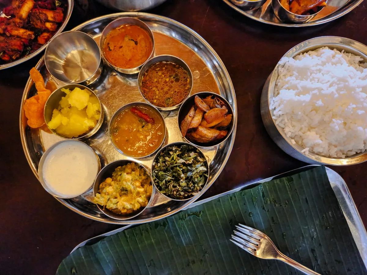 Un thali en coupelles d'inox près d'une feuille de bananier